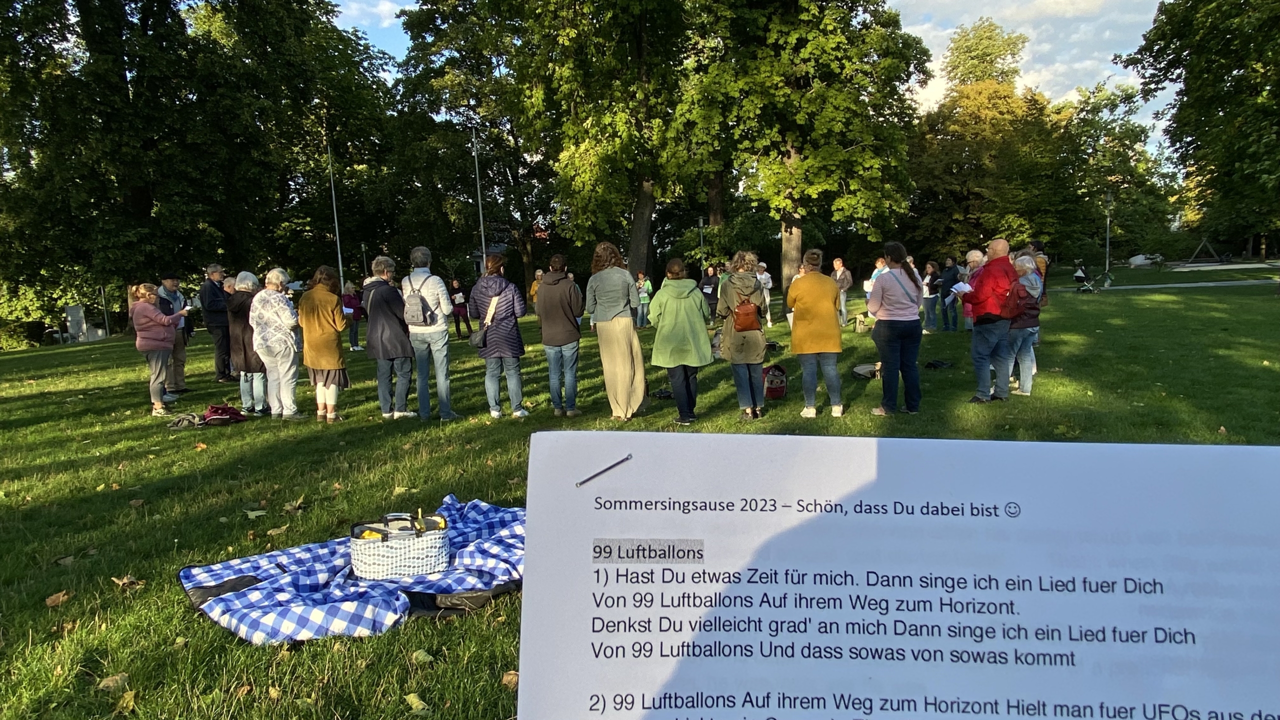 Abendstimmung mit singendem Publikum unter Bäumen